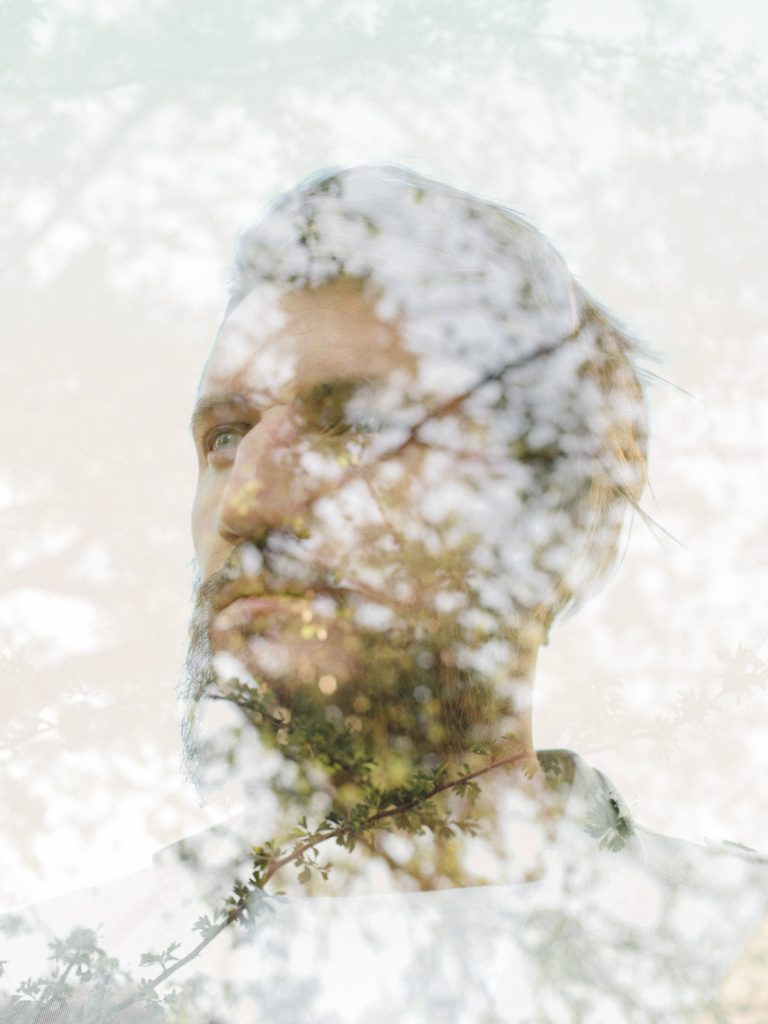 Nachdenklicher Mann im Profil, überlagert von zarten Blüten